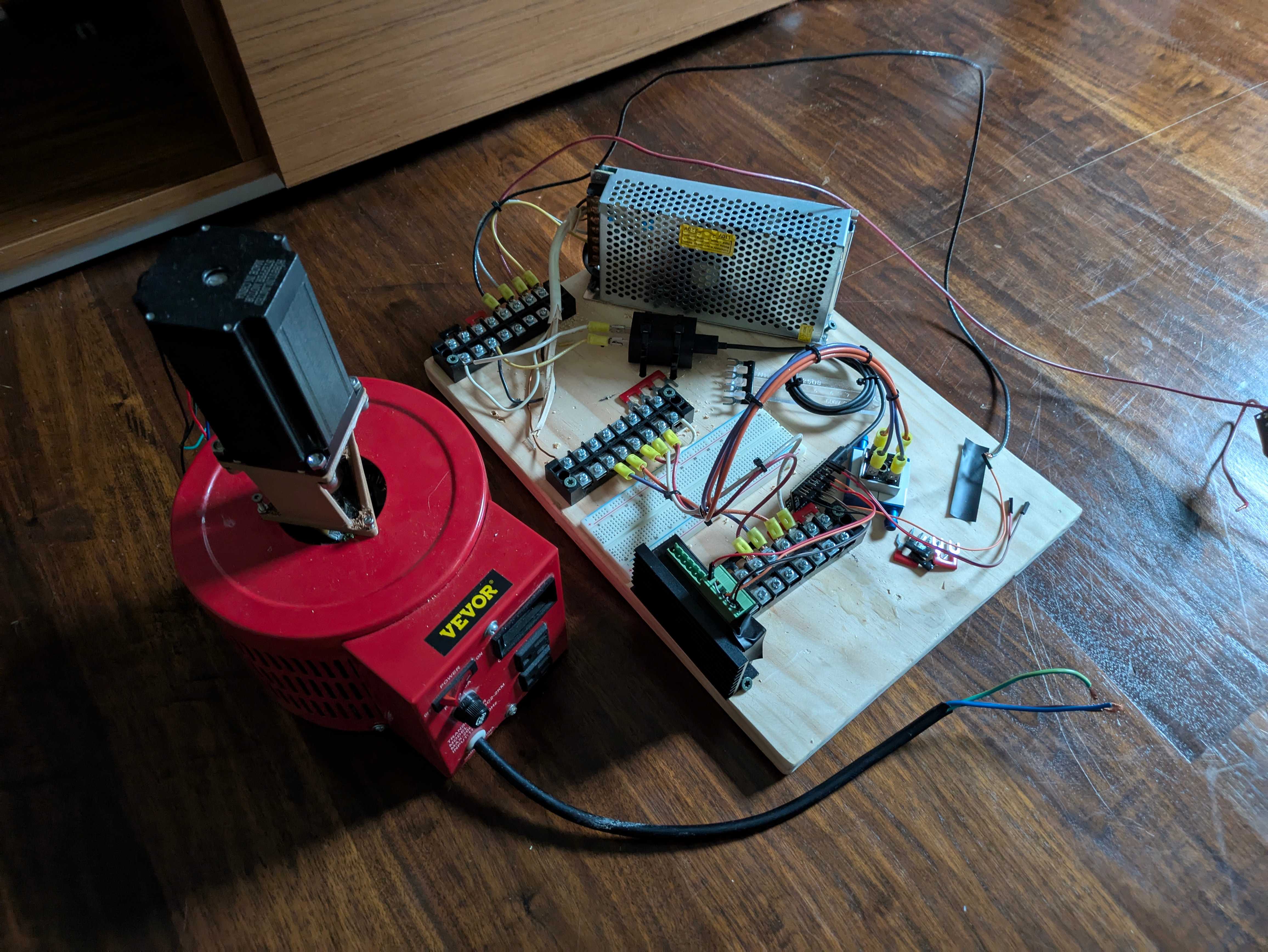 A variac, several busbars, a large stepper motor and controller, and a 12V power supply, all connected together